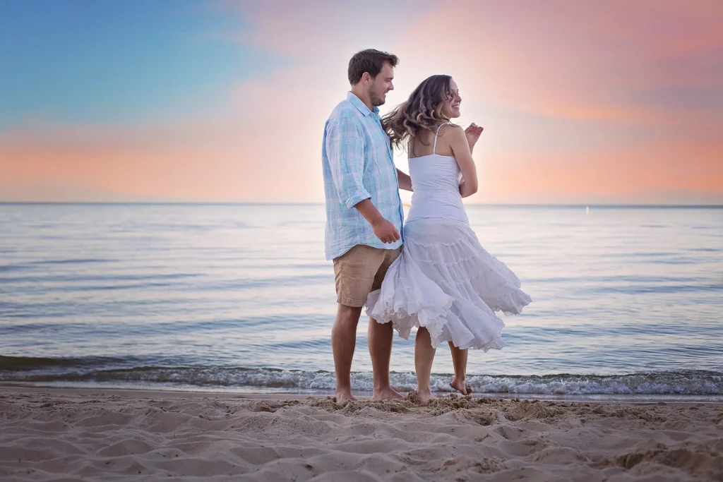 Couple dancing playfully on a sandy beach at sunset, showing romantic chemistry and fun