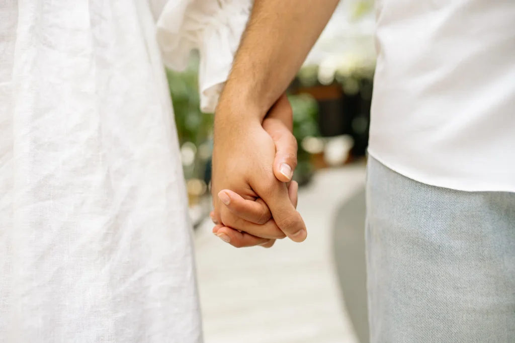 Close-up of a couple in white outfits holding hands while walking together
