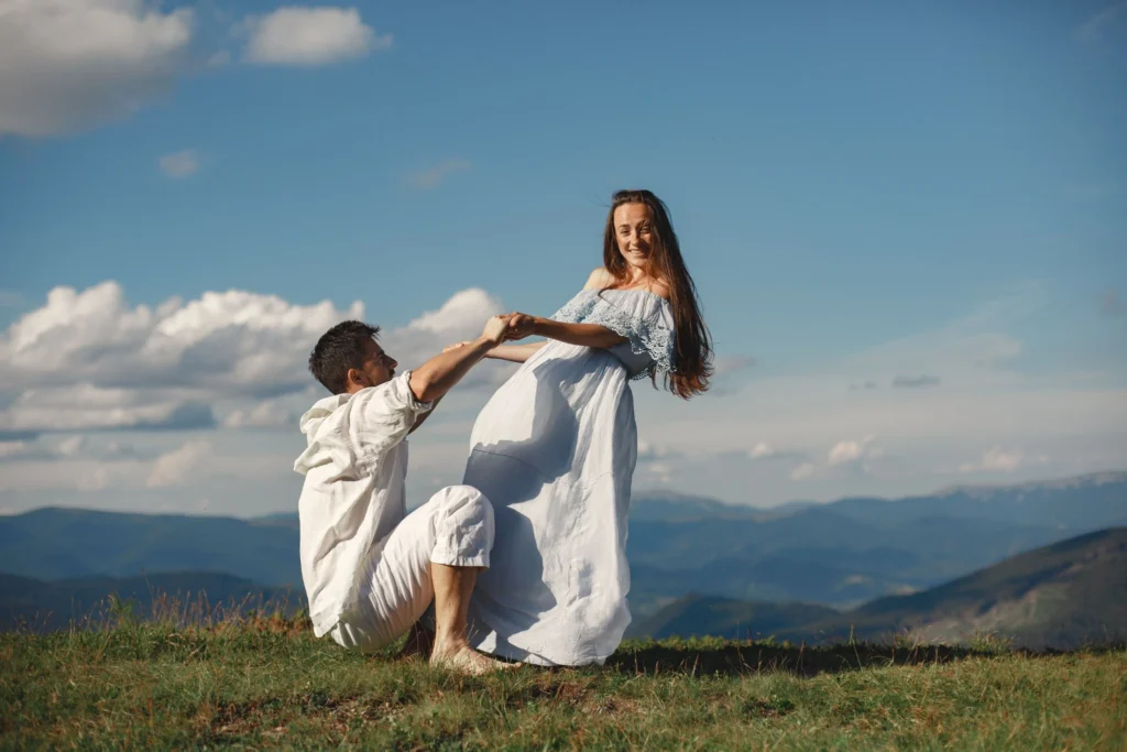 Smiling couple holding hands in a mountain meadow, expressing affection, trust, and emotional connection.