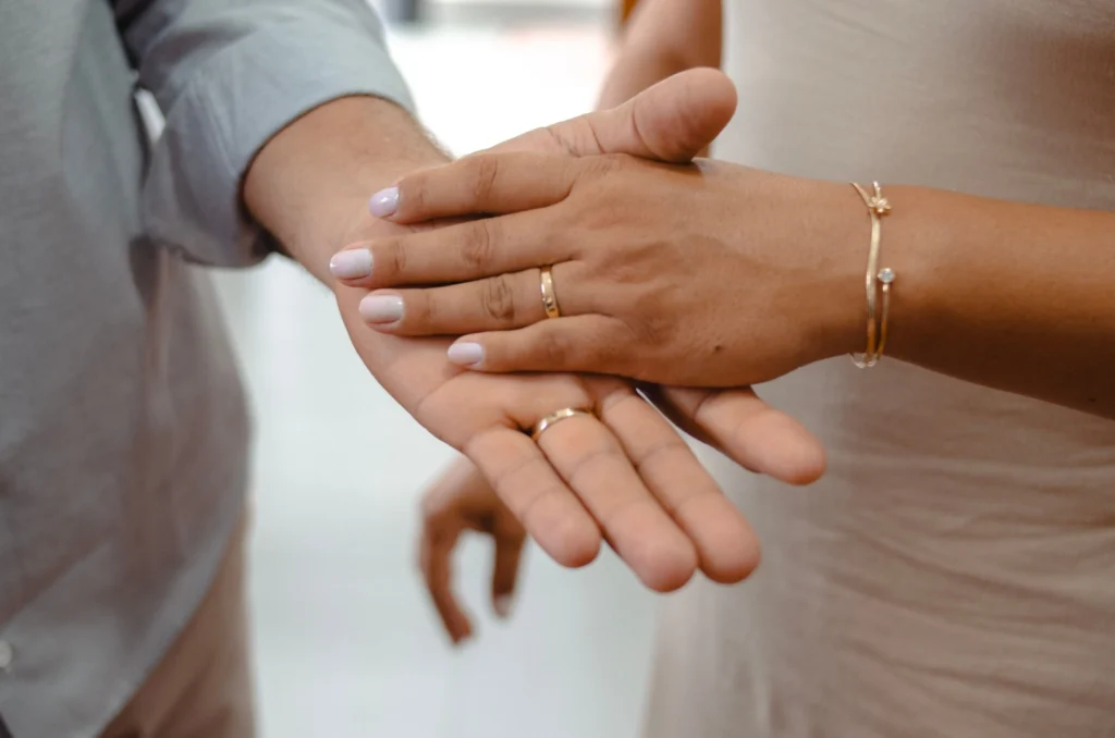 Close-up of a couple holding hands and showing wedding rings.